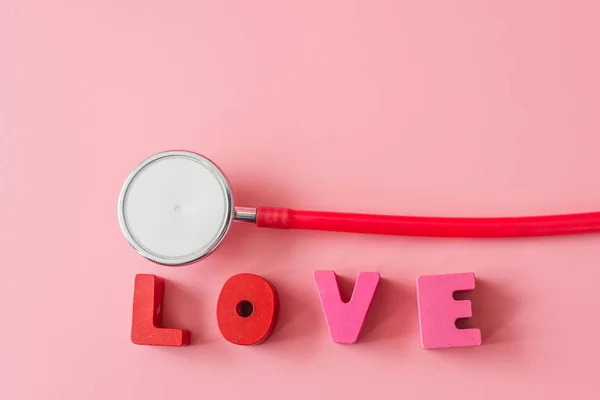 Estetoscopio con amor sobre fondo rosa . — Foto de Stock