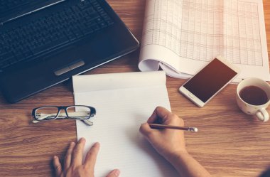 Dizüstü akıllı telefon kahve kalem tutan eller masanın üstüne Kupası