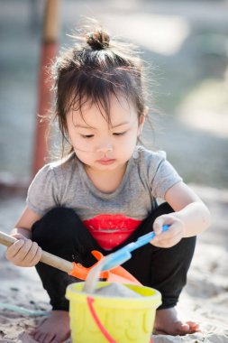 Şirin Asyalı kız iskambil kum güneş ışığı ile.