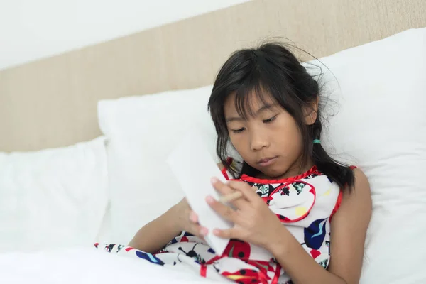 Aziatische meisje iets op papier schrijft. Op bed te leggen. — Stockfoto