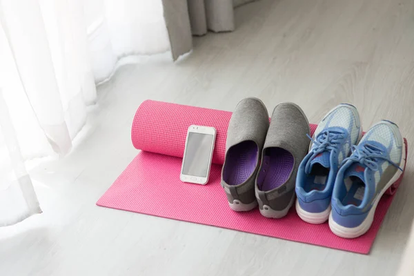 Blue, gray and purple Sport shoes, yoga mat, smartphone on gray