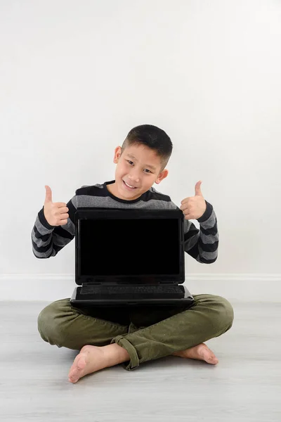 Asiático menino mostrando laptop em branco em casa . — Fotografia de Stock