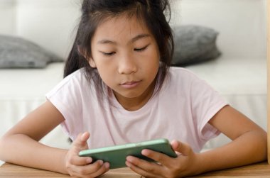 Asyalı kız evde oturma odasında Smartphone kullanarak.