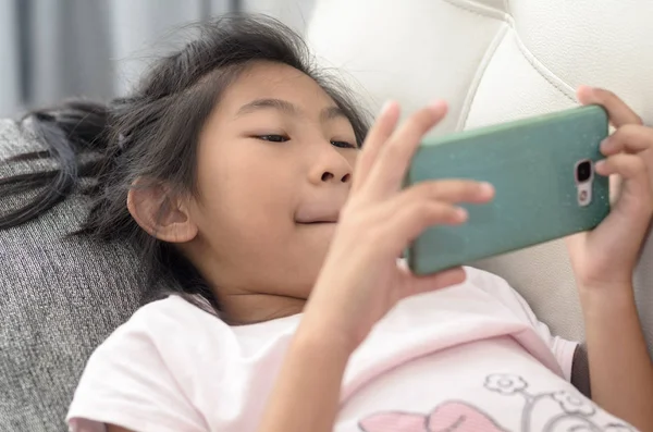 Asiatisk tjej med smartphone och handpåläggning soffa i vardagsrummet på — Stockfoto