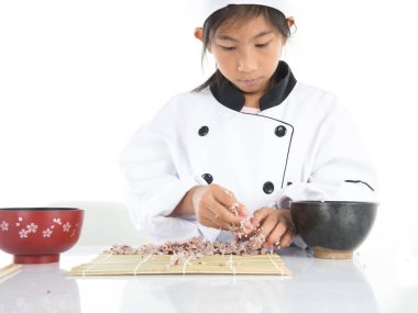 Asyalı kız öğrenme beyaz arka plan üzerinde suşi yapmak nasıl.