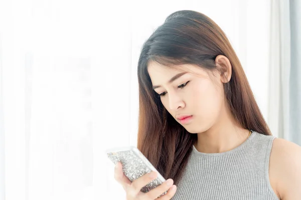 Mulher asiática atraente usando smartphone com luz de janela . — Fotografia de Stock