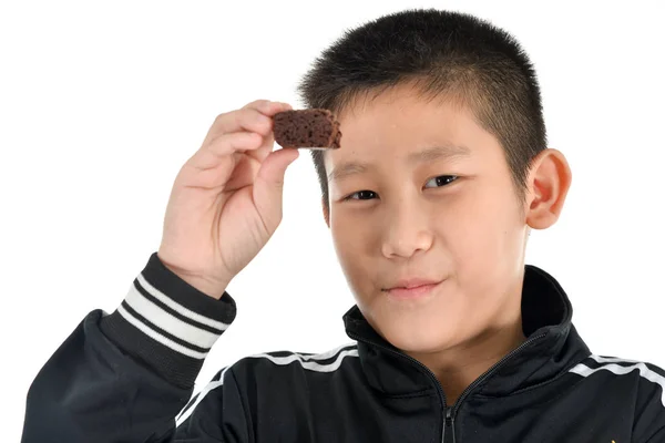 Porträt eines asiatischen Jungen, der Brownie-Kuchen auf weißem Kuchen isst. — Stockfoto