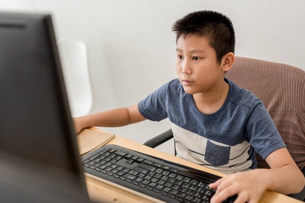 Asian boy playing computer game at home.