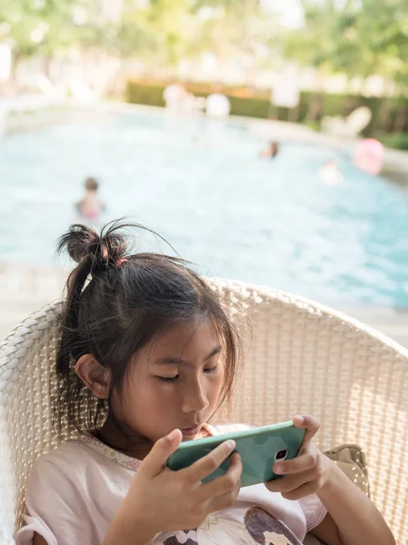 Asiatique fille à l'aide d'un smartphone avec fond de piscine. Techn — Photo