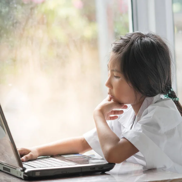Meisje met behulp van Laptop in de buurt van venster thuis — Stockfoto