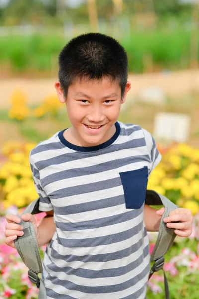 Azjatycki chłopiec z plecakiem w polach kwiat — Zdjęcie stockowe