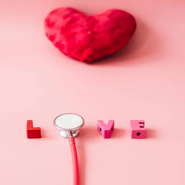 Stetoscopio con amore su sfondo rosso a forma di cuore . — Foto Stock