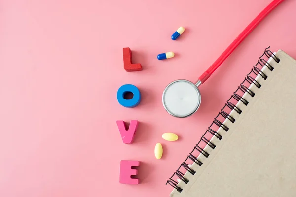 Stethoscope with love and brown book on pink background. — Stock Photo, Image