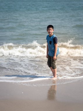 Güneşli bir gün sahilde mutlu Asyalı çocuk.