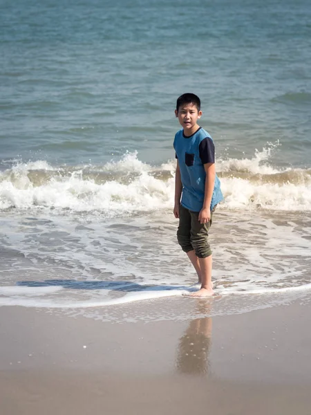 Güneşli bir gün sahilde mutlu Asyalı çocuk.