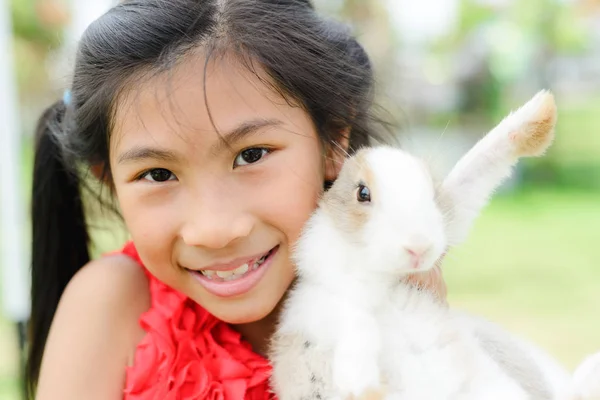 Asiática chica hold y beso conejo al aire libre . —  Fotos de Stock