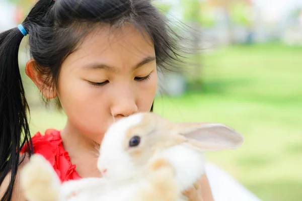 Азиатка держит и целует кролика на открытом воздухе . — стоковое фото
