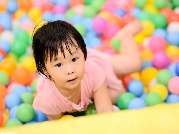 Niño asiático feliz con coloridas bolas de plástico juguete — Foto de Stock