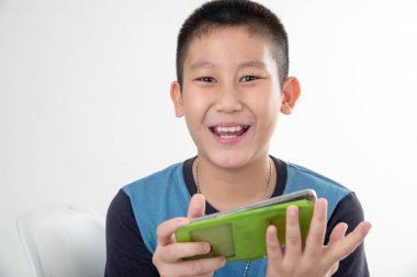 Smartphone kullanarak ve beyaz sandalye üzerinde oturan mutlu Asyalı çocuk