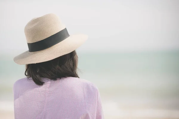 Parte posterior de la mujer con sombrero de paja relajarse en la playa —  Fotos de Stock