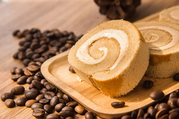 Rolo de bolo de café e grão de café com mesa de madeira e janela li — Fotografia de Stock