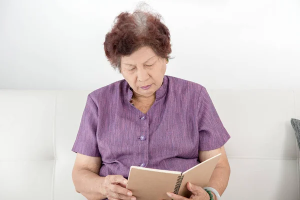 Asian kobieta senior, czytanie książki w domu. — Zdjęcie stockowe