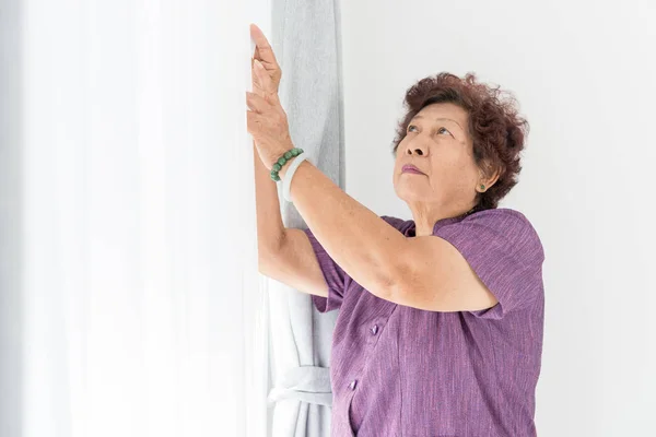 아시아 고위 여자 가까이 집에서 창 근처 화이트 커튼. — 스톡 사진