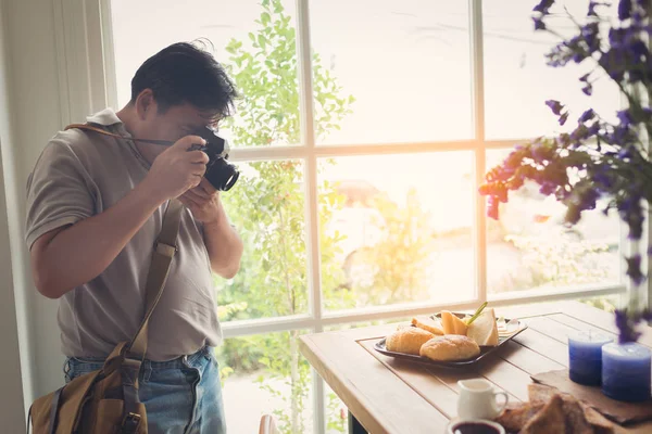 Fotógrafo tirando foto de comida perto da janela no café . — Fotografia de Stock
