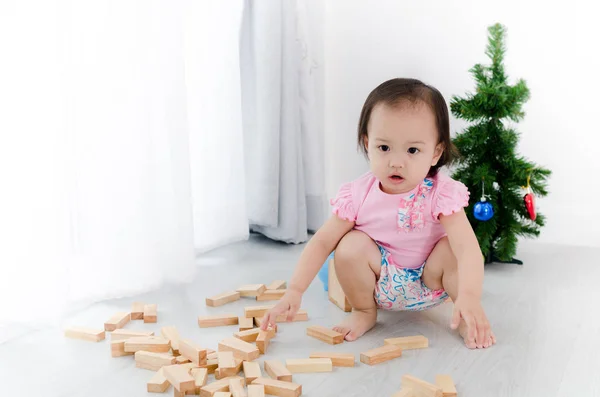 Asiatisk tjej spelar träblock på golvet med julgran — Stockfoto