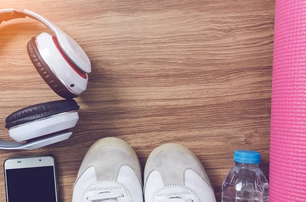 Sport shoes bottle of water, headphone, yoga mat and smart phone — Stock Photo, Image