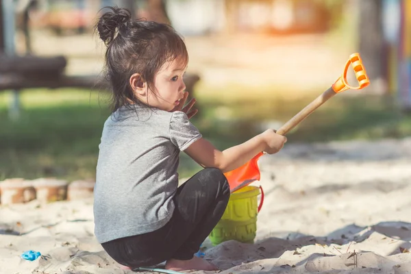 Asiatico ragazza giocare sabbia a parco giochi all'aperto con giorno luce . — Foto Stock