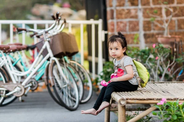 Azjatyckie dziewczyny z plecak siedzi na drewnianym krześle w parku wit — Zdjęcie stockowe