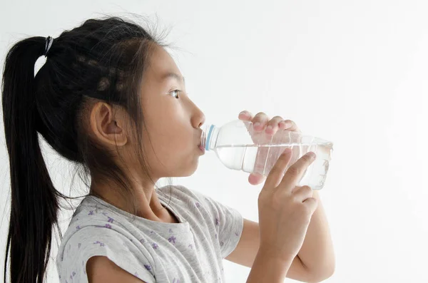 Girl drinking a bottle of water on white background. — Stock Photo, Image