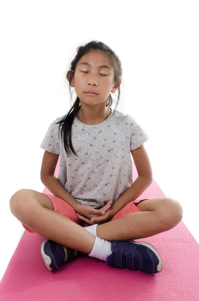 Chica haciendo meditación sobre estera de yoga rosa con fondo blanco . — Foto de Stock