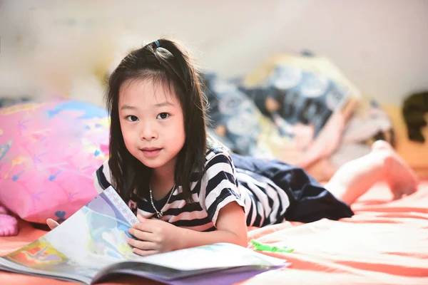 Aziatische meisje liggend op bed en het lezen van een boek. — Stockfoto