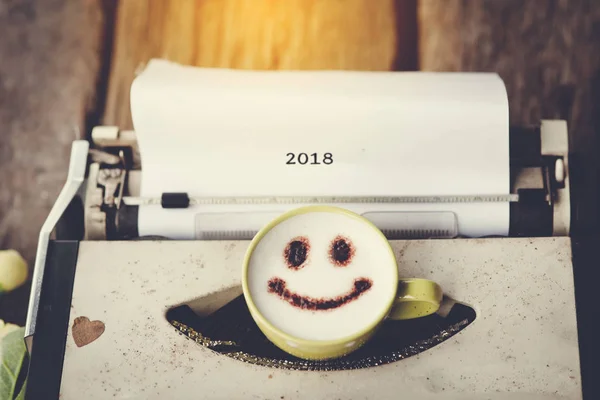 Typewriter with happy face coffee cup with blurry message 2018, — Stock Photo, Image