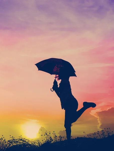 Motion blur jumping Umbrella girl with sunset silhouette — Stock Photo, Image