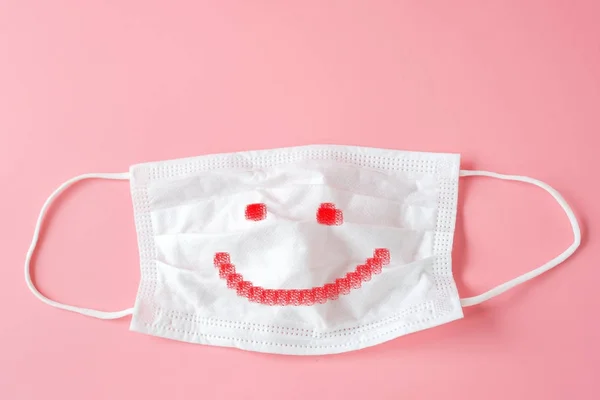 Happy face on Protective white face mask on pink background. — Stock Photo, Image