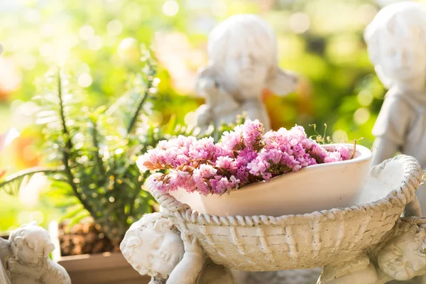 Flor roxa na estátua potted velha branca no jardim com ligh — Fotografia de Stock