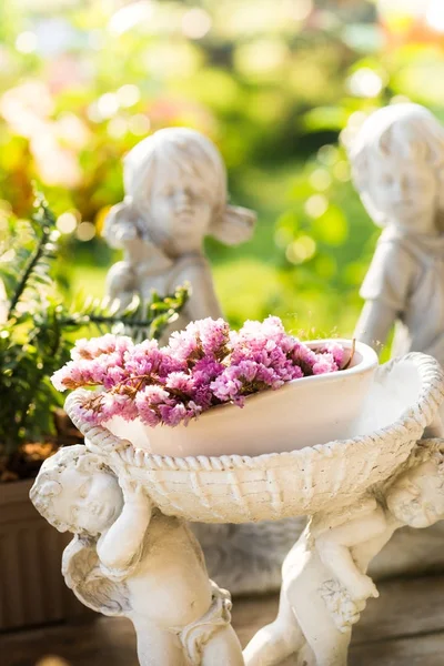 Flor roxa na estátua potted velha branca no jardim com ligh — Fotografia de Stock