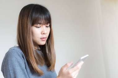 Asyalı kadın akıllı telefon duvar ile kullanma