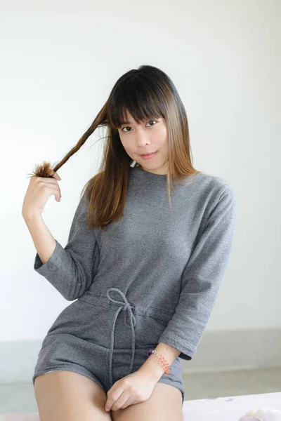 Ázsiai nő ül ágyas, és játszik a haját — Stock Fotó