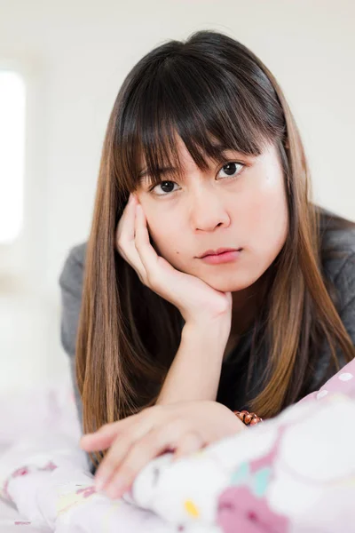 Asiatisk kvinna läser tidningen på sängen hemma. — Stockfoto