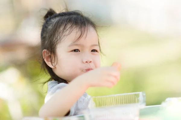 Asiatico ragazza eationg salsiccia in il parco all'aperto . — Foto Stock