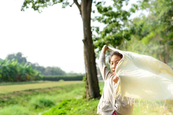 Heureuse fille asiatique tenant écharpe dans le parc en plein air avec matin — Photo