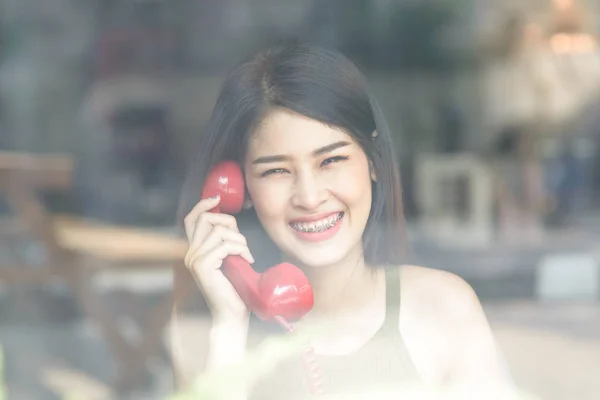 Feliz mujer asiática con frenos y sosteniendo rojo vintage teléfono, t —  Fotos de Stock