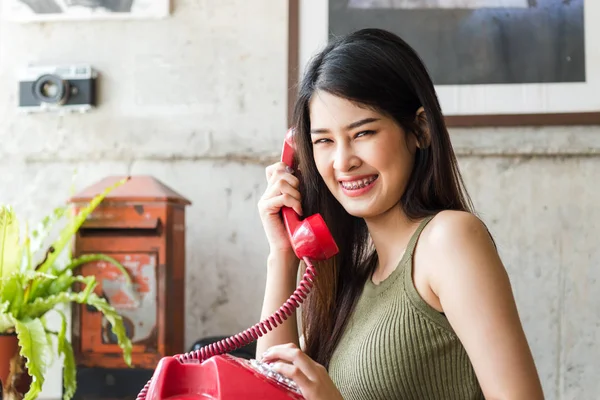 Mujer asiática feliz usando aparatos ortopédicos y sosteniendo teléfono rojo vintage . —  Fotos de Stock