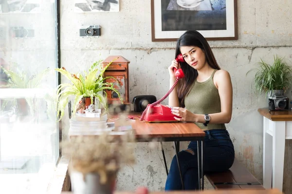 Glücklich asiatische Frau trägt Hosenträger und hält rote Vintage-Telefon. — Stockfoto