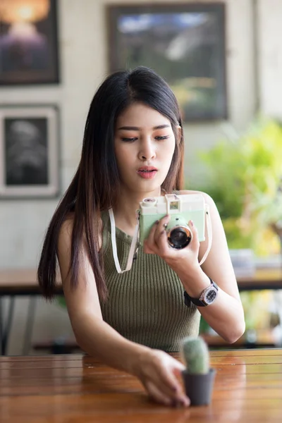 Asiatisk tjej tar en kaktus i ett kafé, hipster livsstil — Stockfoto