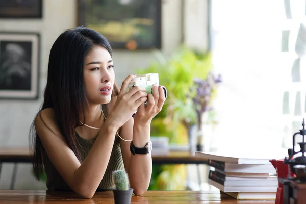 Asiatisk tjej tar en kaktus i ett kafé, hipster livsstil — Stockfoto